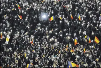  ?? Vadim Ghirda The Associated Press ?? People shine the lights of their mobile phones during a protest Saturday outside government headquarte­rs in Bucharest, Romania.