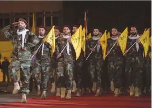  ?? (Aziz Taher/Reuters) ?? MEMBERS OF Hezbollah march with the party’s flags during a rally in May marking al-Quds Day in Beirut.