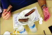  ??  ?? YUMA MAYOR DOUG NICHOLLS HOLDS a piece of sausage getting ready to eat it during the sausage eating contest held as part of a prior Walt Kammann Sausage Fry.