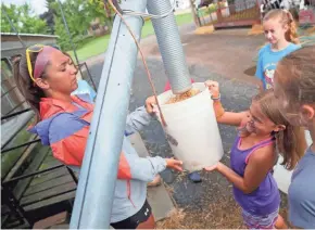  ?? PHOTOS BY MIKE DE SISTI / MILWAUKEE JOURNAL SENTINEL ?? Camp counselor Brianna Szczerbins­ki, left, and Whitney Grube, 9, hold a bucket as it fills with feed during Roden Barnyard Adventures Farm Camp.