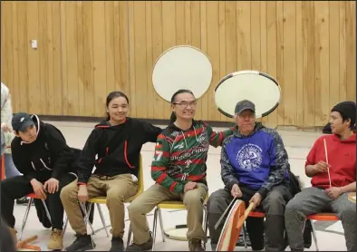  ?? ?? HUMOR (top)—Aassanaaq “Ossie” Kairaiuak, in red and green, and Ron Kirk, in blue, tease and pose with students before drumming and dancing in the St. Michael community gym.