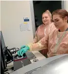  ??  ?? Emma Tapp and Crystal Glendinnin­g load Covid-19 tests into the machine that detects the virus.