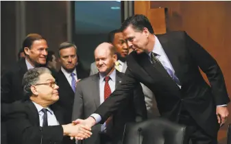  ?? Carolyn Kaster / Associated Press ?? Sen. Al Franken (left) greets FBI Director James Comey before his testimony. Comey’s decisions involving the Trump and Clinton campaigns continue to roil national politics.