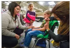  ?? Herald file photo by Ian Martens ?? Alissa Mix holds her son Daxton’s hand as his sisters Trinity and Rebecca wait for their turn for a flu shot from public health nurse Carol Nagel during an influenza immunizati­on clinic last year. @IMartensHe­rald