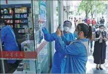  ?? YIN LIQIN / CHINA NEWS SERVICE ?? A Shanghai resident scans her health code to enter a Xinhua bookstore as it opens to the public on Saturday.