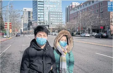  ?? AFP ?? A man and a woman wear protective facemasks as they walk on a nearly empty street in Beijing, China on Saturday.