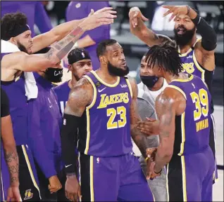  ?? Associated Press ?? FINALS — Los Angeles Lakers’ LeBron James (23), Dwight Howard (39) and other players celebrate during a timeout late in the second half of an NBA conference final playoff basketball game against the Denver Nuggets on Saturday in Lake Buena Vista, Fla.