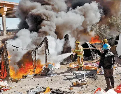  ?? REUTERS ?? Bomberos apagan casas de campaña que fueron quemadas durante el desalojo.