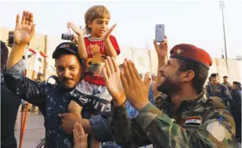  ??  ?? An Iraqi police officer carries a girl as security forces celebrate in West Mosul on Sunday.