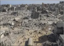  ?? MOHAMMED HAJJAR — THE ASSOCIATED PRESS ?? Palestinia­ns walk through the destructio­n Monday left by the Israeli air and ground offensive on the Gaza Strip near Shifa Hospital in Gaza City.