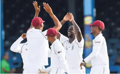  ?? CWI MEDIA/RANDY BROOKS ?? Windies pacer Kemar Roach (second right) celebrates with teammates after taking a wicket on yesterday’s second day of the first Test against Sri Lanka at Queen’s Park Oval in Trinidad.