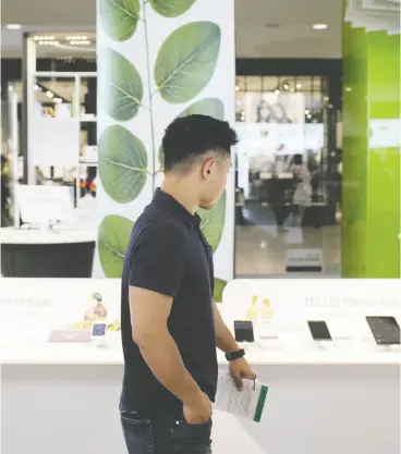  ?? BRENT LEWIN / BLOOMBERG FILES ?? A customer browses at a Telus store in Toronto. Investors feel the economy is on track for a full recovery, so they look for any new government to cut back spending support.