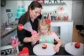  ?? SUBMITTED PHOTO ?? Colleen Kriebel assists a young baker in adding the perfect decorative touches to a cupcake.