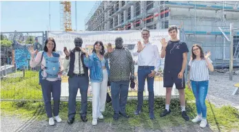  ?? FOTO: GYMNASIUM WILHELMSDO­RF ?? Kathrin Szymanski, Moses Sandy, Sarah Matzenmill­er, Dick Mugisa, Michael Dörmann, Felix Gittinger und Laura Abrell vor dem Neubau des Gymnasiums.