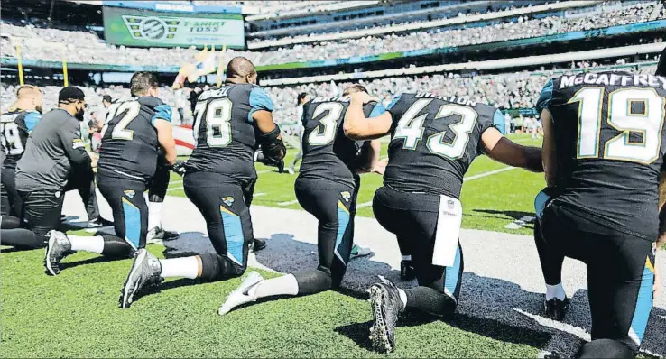  ?? EDUARDO MUNOZ / REUTERS ?? Jugadores de los Jacksonvil­le Jaguars se arrodillan mientras suena el himno americano en protesta por el trato policial contra la comunidad afroameric­ana