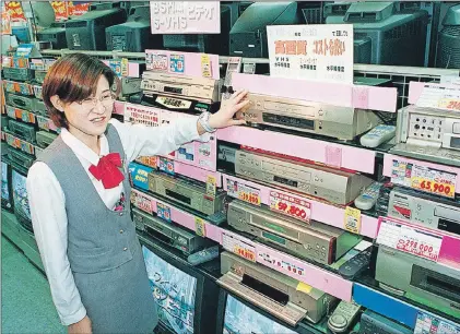  ??  ?? In this October 1998 photo, a salesclerk shows high quality VHS video casette recorders at a home and electrical appliance store in Osaka. Japanese electronic­s maker Funai Electric Co. says it’s yanking the plug on the world’s last video cassette...