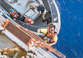  ?? JONATHAN CLAY/U.S. NAVY ?? Tasha Fuiava, who’d been at sea since May on a damaged sailboat with a companion, climbs aboard the USS Ashland after the Navy ship rescued the women and their dogs.