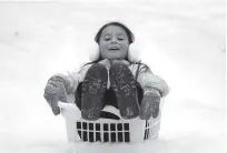  ?? Mark Humphrey / Associated Press ?? Peyton McKinney uses a laundry basket for a sled in Nolensvill­e, Tenn. Much of Tennessee was hit with the severe winter storm.