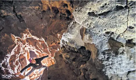  ??  ?? Hayley Clark, of the Subterrane­a Britannica caving group, looks at the ‘witch marks’ she found in Robin Hood’s cave, Creswell Crags, believed to be an entrance to the underworld