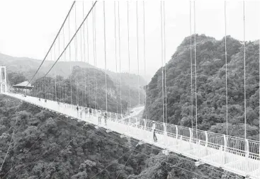  ?? NHAC NGUYEN/GETTY-AFP ?? Bridge for the brave: People walk on the newly opened Bach Long glass-bottomed bridge Friday in northwest Vietnam’s Son La province. The nearly half-mile span, featuring three layers of tempered glass, is suspended almost 500 feet over a lush gorge. An official hopes the bridge will help spur tourism in the province’s Moc Chau district.