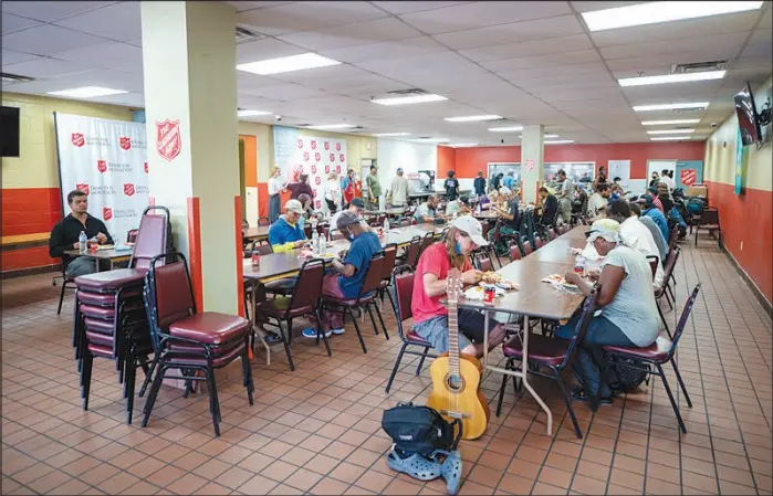  ??  ?? People eat at the Salvation Army’s Lied Dining Hall on Tuesday. The dining hall reopened for the first time since the pandemic shutdown in March 2020.