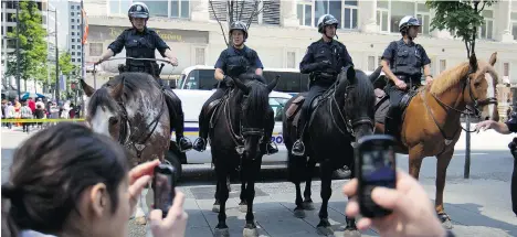  ?? DARRYL DYCK/THE CANADIAN PRESS FILES ?? Bystanders photograph police horses in downtown Vancouver in 2012. Police officers are under increasing scrutiny by citizen journalist­s, and many officers feel such monitoring risks capturing them in a negative light — even though the whole picture...