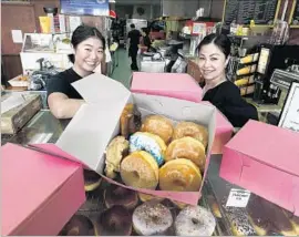  ?? Allen J. Schaben Los Angeles Times ?? SUSAN LIM, right, owner of Rose Donuts & Cafe, and her daughter, Amanda Tang, with the pink doughnut boxes at their San Clemente shop.