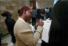  ?? WILFREDO LEE — THE ASSOCIATED PRESS FILE ?? Job applicant Esta Williams, center, uses Tracy Simeton’s back to fill out a questionna­ire as they wait in line at the Seminole Hard Rock Hotel & Casino Hollywood during a job fair in Hollywood, Fla.
