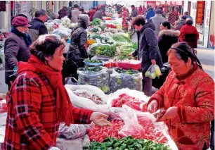  ?? — AFP ?? Chinese customers buy vegetables at a market in Lianyungan­g. China needs to drive domestic wages higher to allow for the consumptio­n share of its economy to grow.