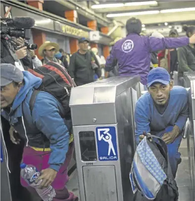  ?? AFP / RODRIGO ABAD ?? Algunos miembros de la caravana pasan por debajo de los tornos en una estación de Ciudad de México.