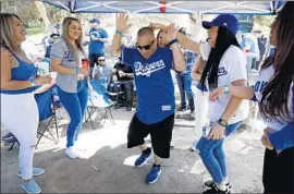  ?? Gary Coronado Los Angeles Times ?? LUIS ZAMORA of Ontario, center, dances with other Dodgers fans to the music of Banda Tomateros de Culiacan at a tailgating party at Elysian Park.