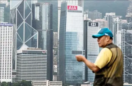  ?? XAUME OLLEROS / BLOOMBERG ?? A resident looks at a row of skyscraper­s, including the AIA Central building, the headquarte­rs of AIA Group, in Hong Kong’s financial district.