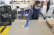  ??  ?? Doreen Rafas disinfects a workspace, as the new rules require, at the Farmstead warehouse in August.