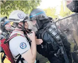  ?? LEWIS JOLY/AP ?? Police officers in riot gear confront a first aid volunteer Sunday at a May Day demonstrat­ion in Paris. Protesters demanded that government do more to help workers.