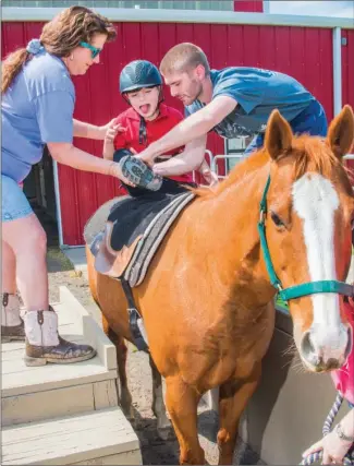  ?? WILLIAM HARVEY/RIVER VALLEY & OZARK EDITION ?? Lori Pelham, left, a volunteer at Equestrian Zone, and physical therapist Tanner Goulet help Oswaldo Bolanos, 10, as they get ready for a horseback ride, which is used to help Bolanos calm down with his disabiliti­es.