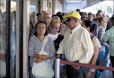  ?? AP/FERNANDO LLANO ?? Customers wait to get new banknotes Tuesday at a government bank in Maracaibo, Venezuela. The country has devalued its currency 95 percent and taken other economic measures to confront hyperinfla­tion.