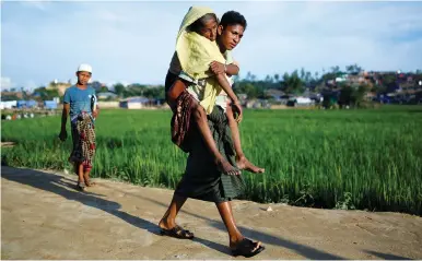  ??  ?? A ROHINGYA refugee carries his mother on his back yesterday at a refugee camp near Cox’s Bazar, Bangladesh.