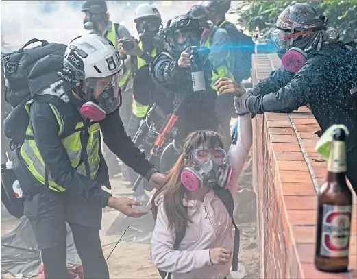  ??  ?? Police officer sprays protesters with identifyin­g blue dye as they try to flee after occupying Hong Kong Polytechni­c University campus on Monday
