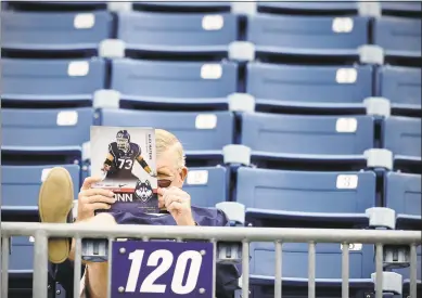  ?? Jessica Hill / Associated Press ?? A fan reads a program before an NCAA college football game between UConn and Boise State at Rentschler Field in East Hartford on Sept. 13, 2014.