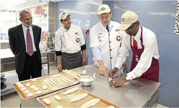  ??  ?? Kamalanath­an trying his hands at moulding bread while being guided by MIB chairman Don Yong.