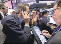  ?? RICHARD DREW/ASSOCIATED PRESS ?? Specialist Peter Mazza, center, works with traders on the floor of the New York Stock Exchange. Vanguard’s Total Internatio­nal Stock Index fund returned 9.2 percent for its best quarter in nearly four years.