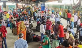  ?? — PTI ?? Migrants wait to board trains to their native places at New Delhi railway station on Tuesday.