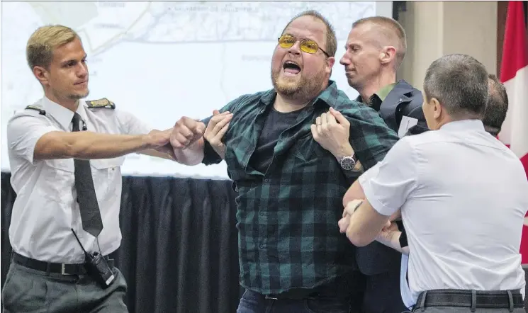  ?? PAUL CHIASSON/THE CANADIAN PRESS ?? Security guards try to restrain a demonstrat­or from interrupti­ng the National Energy Board public hearing into TransCanad­a’s proposed $15.7-billion Energy East pipeline project last August in Montreal. The NEB’s decision to review the project’s effect...