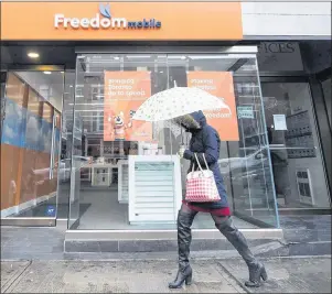  ?? NATHAN DENETTE/THE CANADIAN PRESS ?? A woman walks past a Freedom Mobile store in Toronto on Nov. 24, 2016. Freedom Mobile will begin taking orders for the Apple iPhone X and iPhone 8 models starting Friday, with the smartphone­s in its stores on Dec. 8.