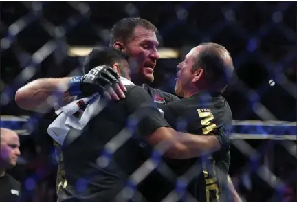  ?? HANS GUTKNECHT — SOUTHERN CALIFORINA NEWS GROUP ?? Stipe Miocic is congratula­ted by his coaches Marcus Marinelli, right, and Pablo Castro after he defeated Daniel Cormier to win the UFC heavyweigh­t title on Aug. 17 in Anaheim, Calif. See a photo collection from the bout at News-Herald.com.