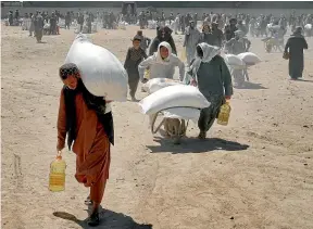  ?? AP ?? Afghans receive food from a Chinese aid group for the Muslim holy month of Ramadan, in Kabul. A new UN report says food insecurity is poised to hit ‘‘appalling’’ new levels worldwide as the Ukraine war affects global food production.