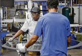  ?? TY GREENLEES / STAFF ?? Workers at Fuyao Glass America finish an automobile windshield in the Moraine plant. Fuyao currently employs 2,300 workers and expects to need 700 more within three years.