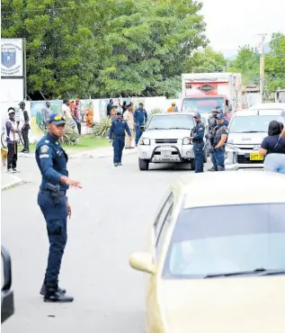  ?? GLADSTONE TAYLOR/MULTIMEDIA PHOTO EDITOR ?? Police officers keep a watchful eye on movements on West Main Drive in Maverley, St Andrew North Western, on Monday.