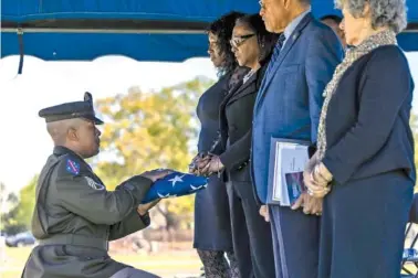  ?? PHOTOS BY ALYSSA POINTER/THE NEW YORK TIMES ?? U.S. Army Staff Sgt. Laurence Henderson, left, presents the flag that covered the coffin of Pvt. Albert King to King’s family Sunday at Porterdale Cemetery in Columbus, Ga.