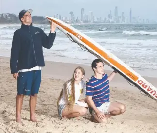  ?? Picture: GLENN HAMPSON ?? Gold Coast City lifeguard Michael Saal offers Brisbane visitors Gemma Turner, 19, and Jack Dickson, 19, shelter from the elements at Burleigh under his board.